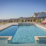Swimming pool with a small raised spa, timber deck and red sun loungers